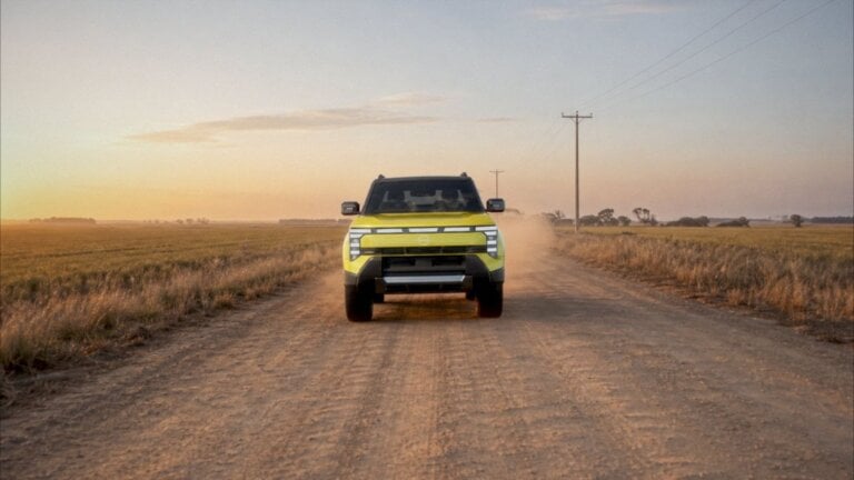 Yellow Nissan Navara Pro PHEV ute driving on a rural gravel road, front view